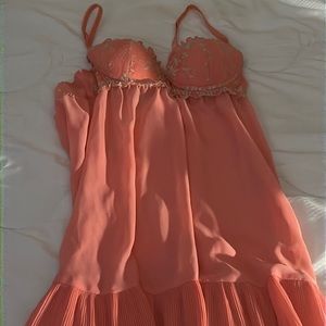 Woman orange sleep wear with gold trimming and ruffle bottom.